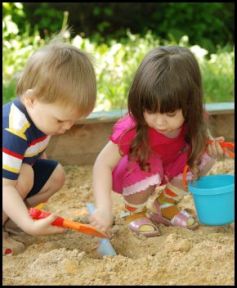 The boy and girl playing to a sandbox